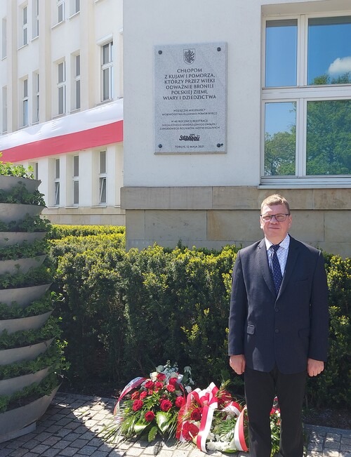 Mirosław Golon składa kwiaty pod pod tablicą, umieszczoną na ścianie gmachu Urzędu Marszałkowskiego.